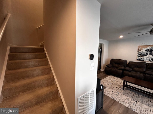 stairs featuring ceiling fan and wood-type flooring