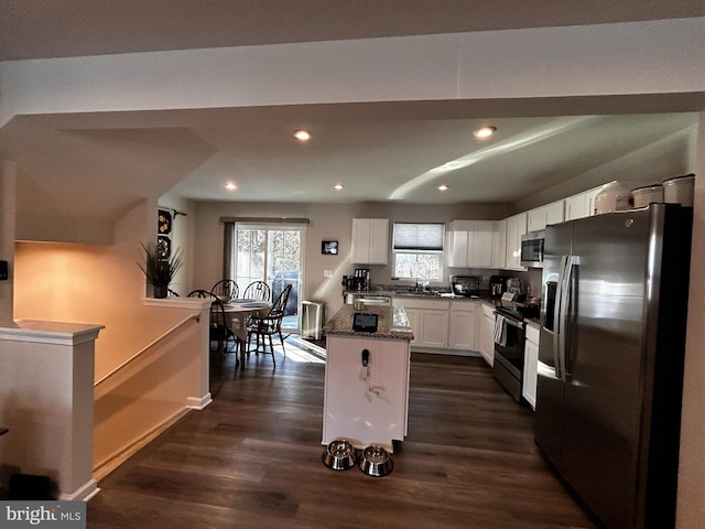 kitchen with sink, a center island, dark stone counters, stainless steel appliances, and white cabinets