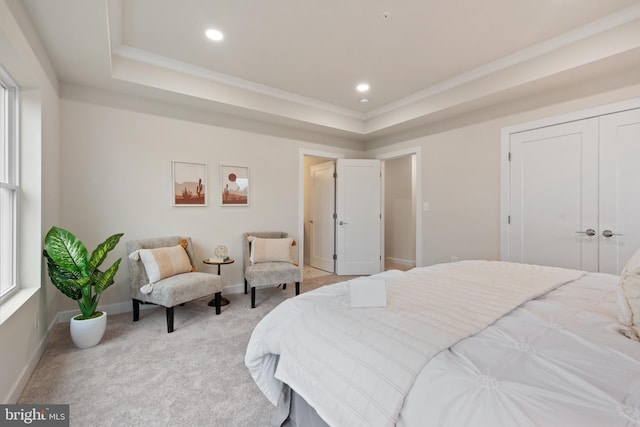 bedroom with ornamental molding, light colored carpet, and a tray ceiling