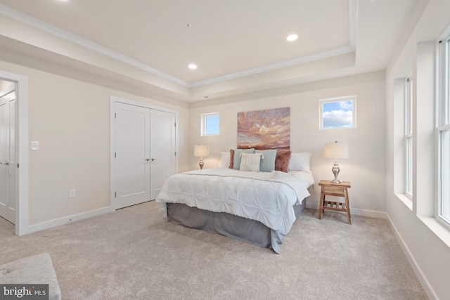 bedroom with ornamental molding, a tray ceiling, and light carpet