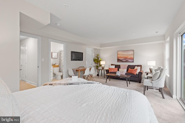 bedroom featuring connected bathroom and light colored carpet