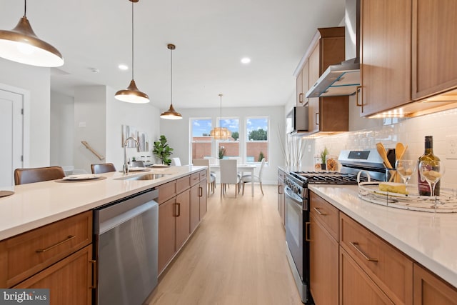 kitchen featuring pendant lighting, sink, stainless steel appliances, decorative backsplash, and wall chimney exhaust hood