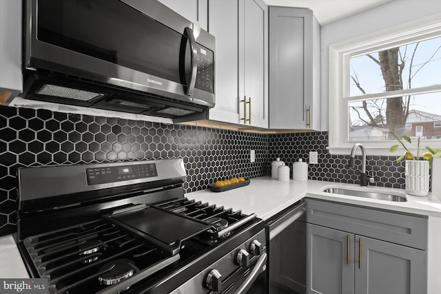 kitchen featuring stainless steel appliances, gray cabinets, sink, and decorative backsplash