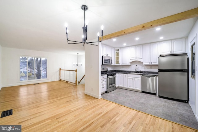 kitchen featuring white cabinets, decorative light fixtures, a chandelier, and appliances with stainless steel finishes