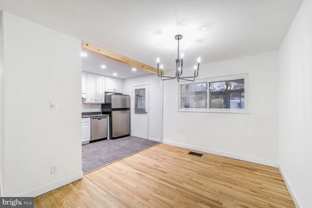 unfurnished dining area with beamed ceiling, a chandelier, and light wood-type flooring