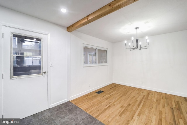 unfurnished dining area featuring a healthy amount of sunlight, hardwood / wood-style floors, beamed ceiling, and an inviting chandelier