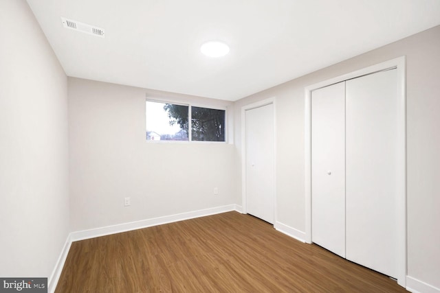 unfurnished bedroom with hardwood / wood-style flooring and multiple closets