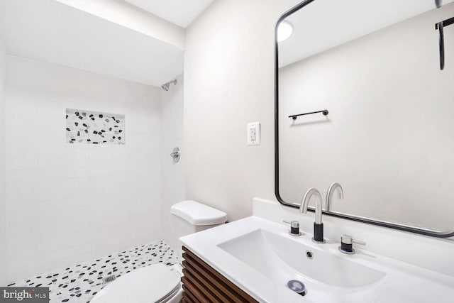 bathroom featuring vanity, toilet, and a tile shower