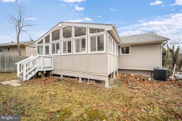 rear view of house featuring central AC and a lawn