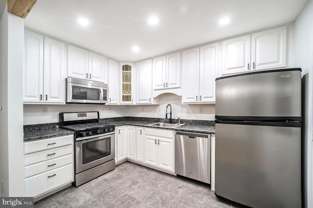 kitchen featuring stainless steel appliances, white cabinetry, sink, and dark stone counters