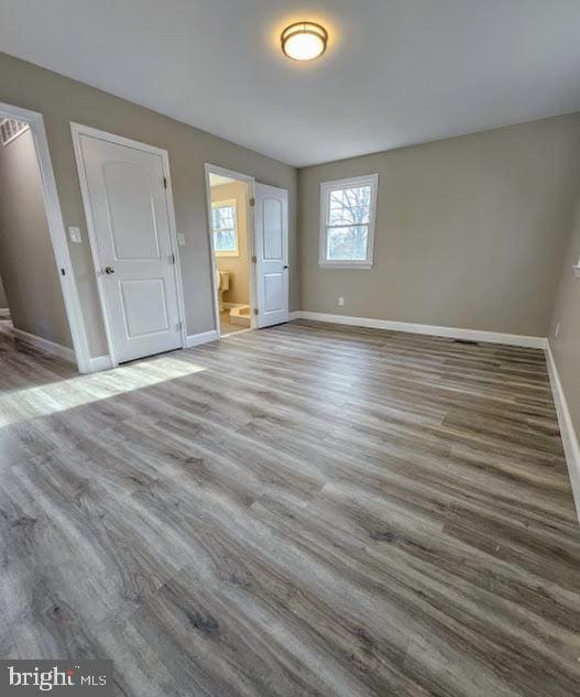 unfurnished bedroom featuring wood-type flooring and ensuite bathroom