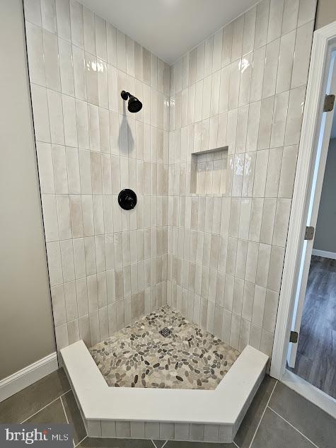 bathroom with tile patterned flooring and tiled shower