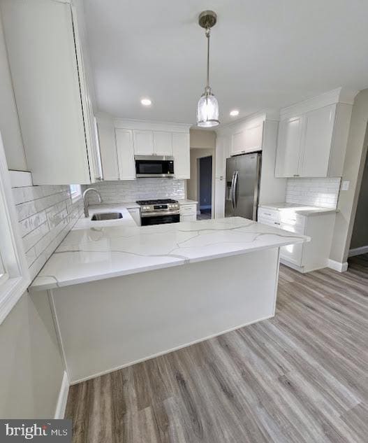 kitchen with white cabinetry, appliances with stainless steel finishes, sink, and kitchen peninsula