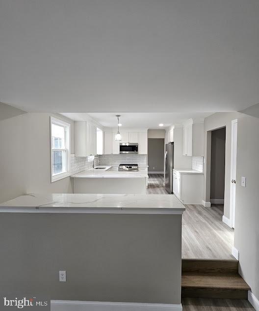 kitchen featuring sink, appliances with stainless steel finishes, hanging light fixtures, white cabinets, and kitchen peninsula