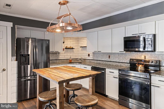 kitchen featuring white cabinetry, appliances with stainless steel finishes, crown molding, and dark stone counters