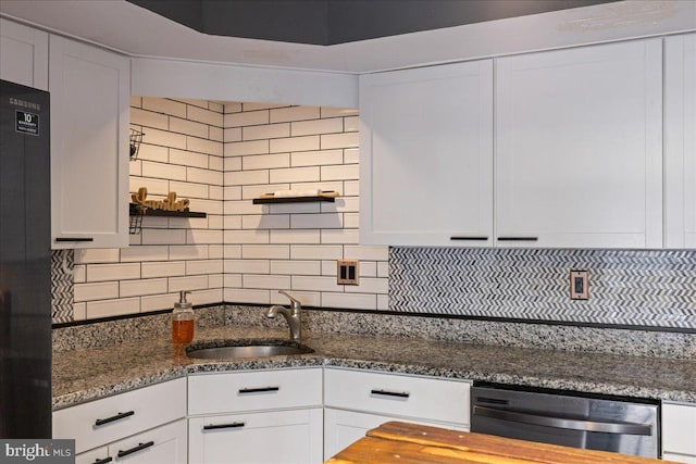 kitchen with white cabinetry, backsplash, sink, and dark stone countertops