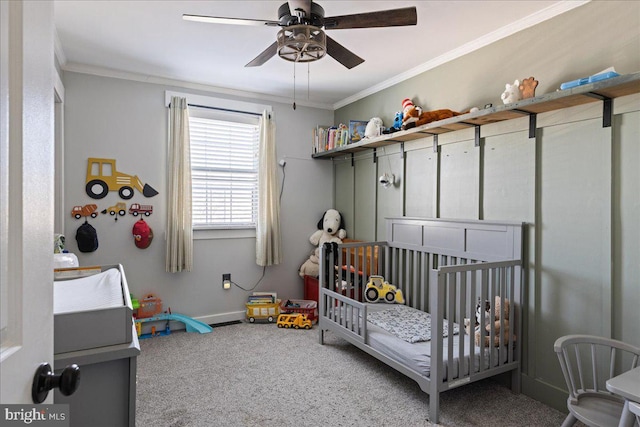 carpeted bedroom with a crib, ornamental molding, and ceiling fan