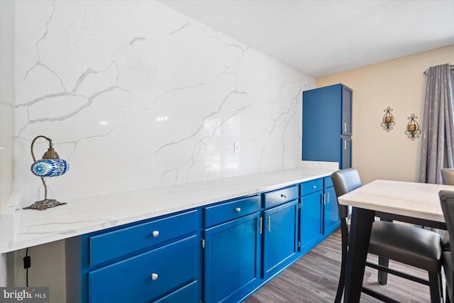 interior space with light stone countertops, blue cabinetry, and dark hardwood / wood-style floors