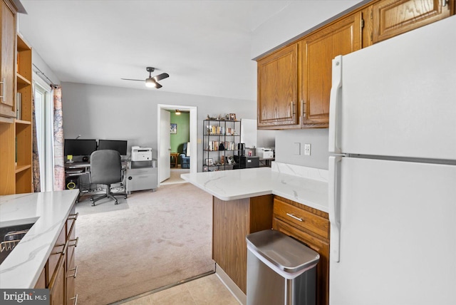 kitchen with light carpet, kitchen peninsula, ceiling fan, and white fridge