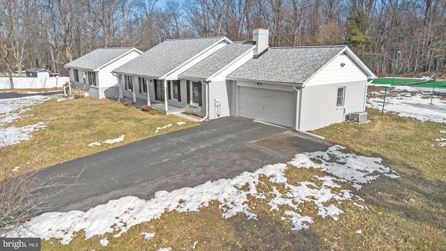 ranch-style house with cooling unit, a garage, covered porch, and a lawn