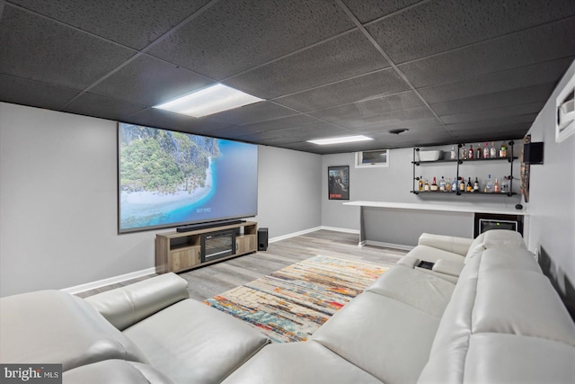 cinema with a drop ceiling, wood-type flooring, and bar area