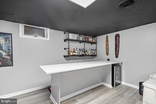 bar with a drop ceiling, hardwood / wood-style floors, and wine cooler