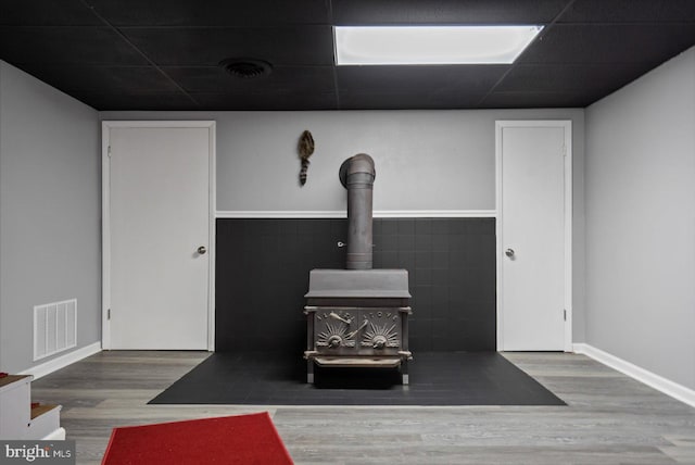 details with a wood stove, hardwood / wood-style floors, and a drop ceiling