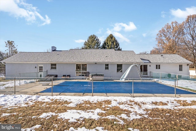 snow covered rear of property featuring a covered pool