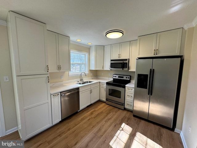 kitchen featuring white cabinetry, sink, light hardwood / wood-style flooring, and stainless steel appliances