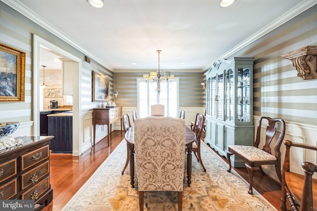 dining room featuring ornamental molding, wood-type flooring, and a chandelier