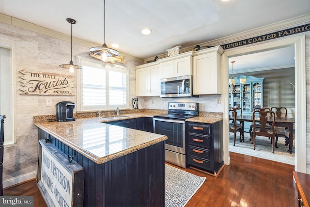 kitchen featuring appliances with stainless steel finishes, pendant lighting, white cabinetry, sink, and dark wood-type flooring