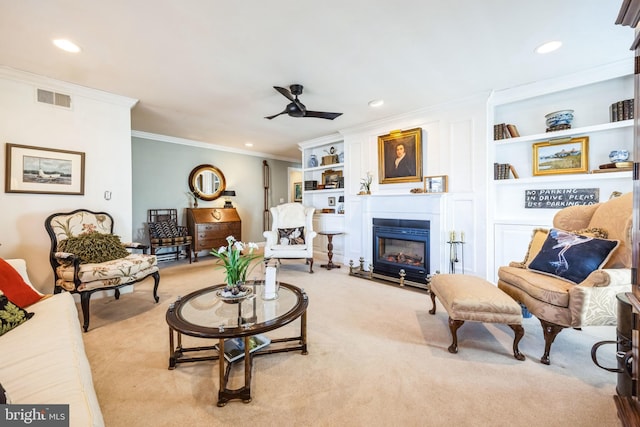 carpeted living room featuring crown molding, built in shelves, and ceiling fan