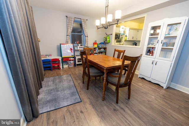 dining space featuring dark wood-type flooring and a chandelier