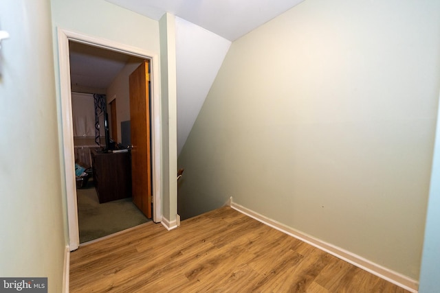 hall with lofted ceiling and light hardwood / wood-style floors