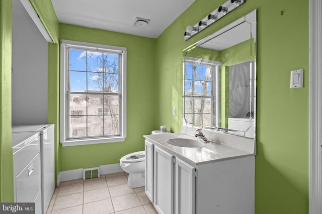 bathroom featuring washing machine and clothes dryer, vanity, toilet, and tile patterned floors