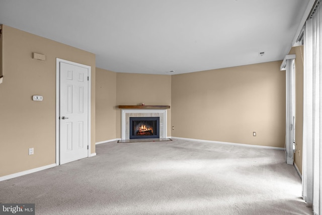 unfurnished living room featuring a tiled fireplace and carpet flooring