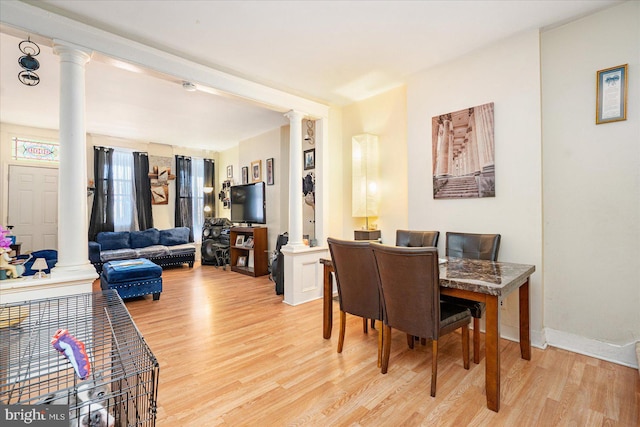 dining space with decorative columns and light wood-type flooring