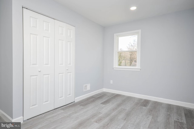 unfurnished bedroom with light hardwood / wood-style flooring and a closet