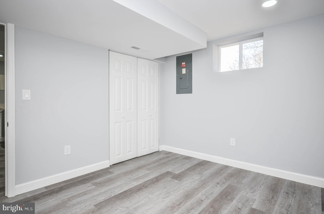 basement featuring electric panel and light hardwood / wood-style floors