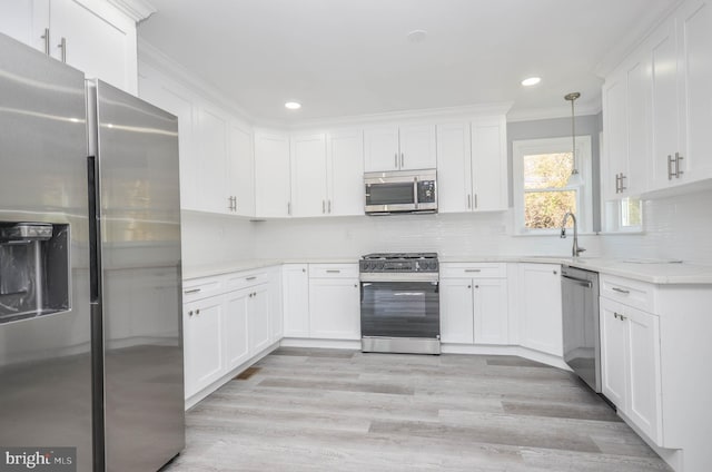 kitchen with white cabinetry, appliances with stainless steel finishes, decorative light fixtures, and tasteful backsplash