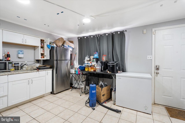 kitchen featuring appliances with stainless steel finishes, sink, light tile patterned floors, and white cabinets