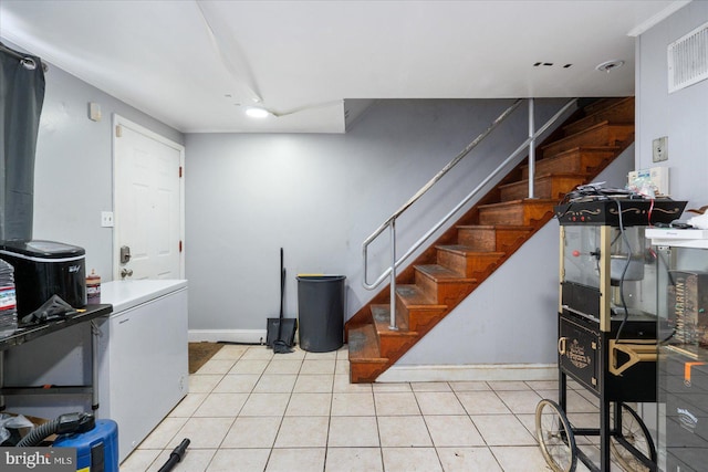 basement featuring light tile patterned floors and fridge