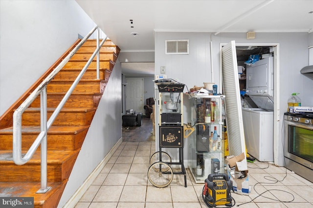 kitchen with stainless steel range with gas cooktop, stacked washer / drying machine, and light tile patterned floors