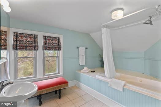 bathroom featuring tile patterned flooring, lofted ceiling, and a washtub