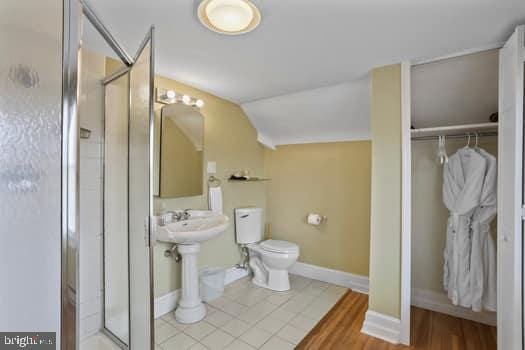 bathroom featuring tile patterned flooring, vaulted ceiling, toilet, and walk in shower