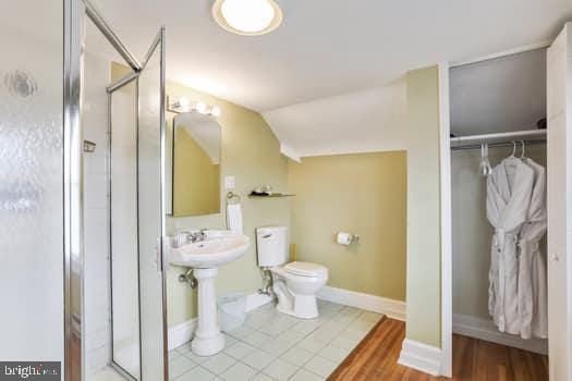 bathroom with lofted ceiling, an enclosed shower, and toilet