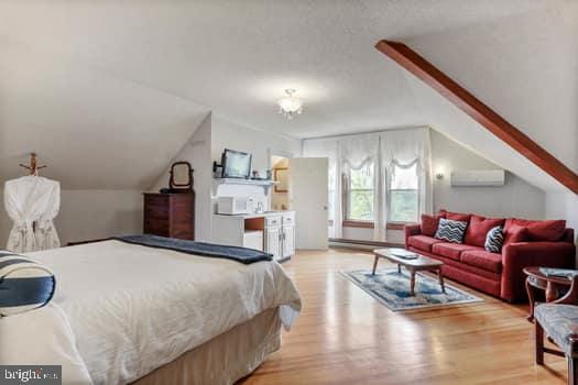 bedroom with vaulted ceiling, access to outside, hardwood / wood-style floors, and a wall unit AC