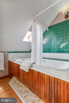 bathroom with hardwood / wood-style flooring and vaulted ceiling