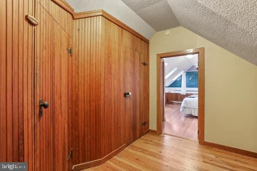 bonus room featuring vaulted ceiling, light hardwood / wood-style flooring, and a textured ceiling