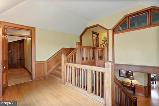 hallway with lofted ceiling and light hardwood / wood-style flooring